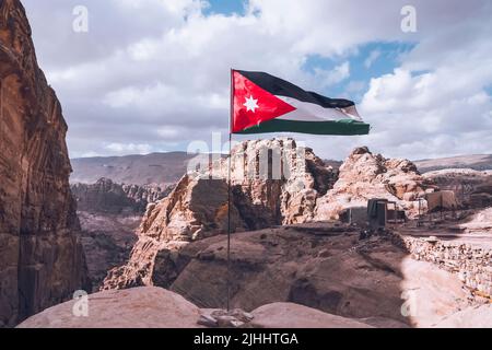 Die Flagge Jordaniens, Dreharbeiten in der alten Steinstadt Petra, auf dem roten Felsenhintergrund, Nahaufnahme, im Freien. Stockfoto