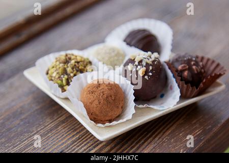 Sortierte, zuckerfreie vegane Trüffel ohne Backen, Mehl und Milch auf Holztisch im Inneren. Natürliche Süßigkeiten. Kaffeepause Stockfoto