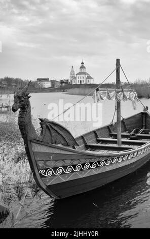 Touristenboot auf dem Wasser. Drakkar auf dem Fluss, Elijah Kirche am Horizont, Architektur des XVIII Jahrhunderts. Susdal, Russland, 2022 Stockfoto