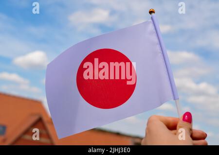 Die weiße Nationalflagge mit dem roten Kreis Japans in der Hand aus nächster Nähe Stockfoto