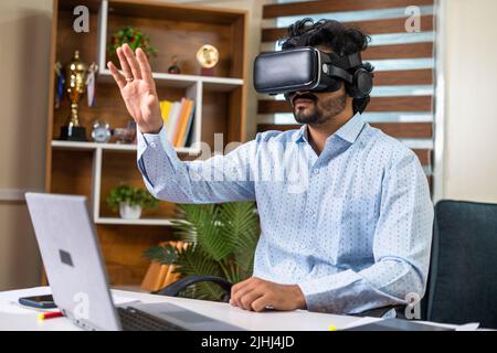 Junger Geschäftsmann, der mit VR- oder Virtual-Reality-Headsets für Meetings im Büro mit Handgesten beschäftigt ist - Konzept der Technologie, Metaverse und futuristisch Stockfoto
