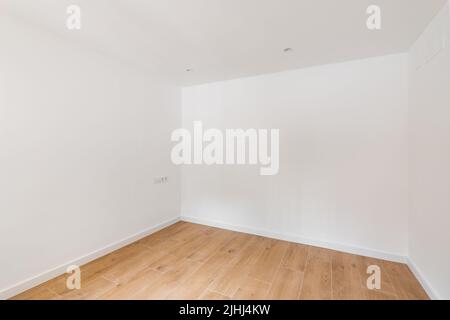 Leeres Zimmer mit Laminatboden und neu lackierter weißer Wand in renovierter Wohnung. Reparatur- und Konstruktionskonzept. Stockfoto