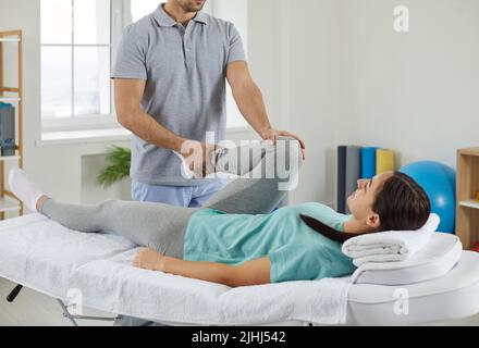 Physiotherapeutin, die mit den Beinen einer jungen Patientin im Rehabilitationszentrum arbeitet. Stockfoto