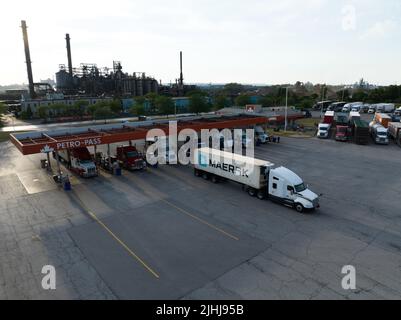 Ein Maersk-Container auf einem Transportfahrzeug verlässt an einem sonnigen Nachmittag eine große Tankstelle in einem Industriebereich. Stockfoto