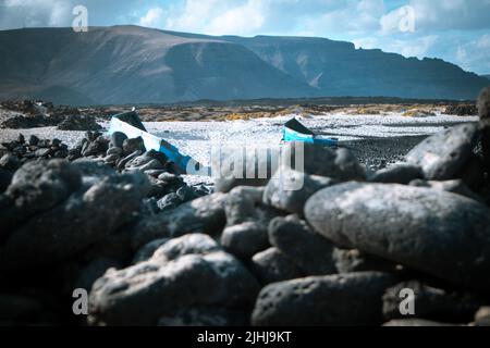 Blaue alte Holzboote am weißen Strand von Caleta del Mojon Blanco. Sandiger Wüstenstrand und zerklüftete Küste. Orzola, Lanzarote, Kanarische Inseln, Spanien Stockfoto