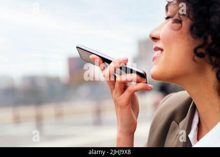Lächelnde Frau, die eine Nachricht mit einem Handy aufzeichnet Stockfoto