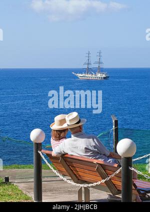 Ältere Paare mit Strohhüten sitzen auf einer Bank und genießen Meerblick, Taurito, Grand Canary, Kanarische Inseln, Spanien, Europa Stockfoto