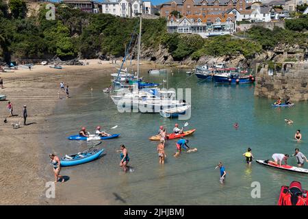 Urlauber genießen den herrlichen Sonnenschein bei einem Aufenthalt im malerischen Newquay Harbour in Cornwall in England im Vereinigten Königreich. Stockfoto