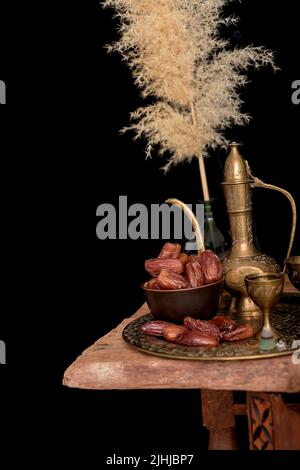 Arabischer Kaffee und Datteln eingerichtet. Schwarzer Hintergrund. Stockfoto