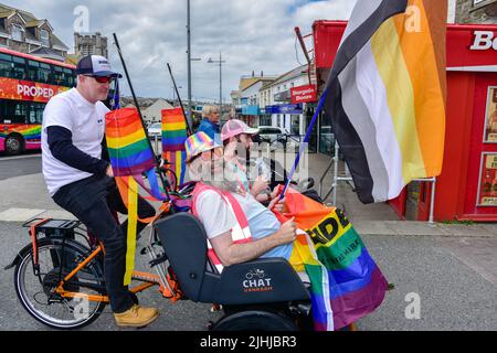 Teilnehmer, die in einer Chat Van Raam Electric Rikscha in der farbenfrohen Cornwall Prides Pride Parade im Zentrum von Newquay in Großbritannien reiten. Stockfoto