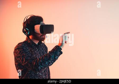 Mann, der die Virtua lrealitäts-Brille trägt und die Augmented Reality erlebt. Berühren der virtuellen Schnittstelle. Studioaufnahme. Hochwertige Fotos Stockfoto