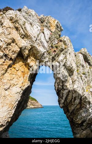 Blick durch einen natürlichen weißen Felsbogen in der Bucht von Porth Wen. Cemaes, Isle of Anglesey, Wales, Großbritannien Stockfoto