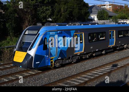 Seitenansicht des vorderen Wagens eines neuen HCMT mit blauer und gelber Metro-Lackierung, während der Zug die Passagiere durch die inneren Vororte Melbournes transportiert Stockfoto