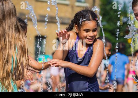 London, Großbritannien - 18. Juli 2022 - Hitzewelle in London, Kinder spielen mit Wasser, um sich an den Brunnen am Granary Square in Kings Cross abzukühlen Stockfoto