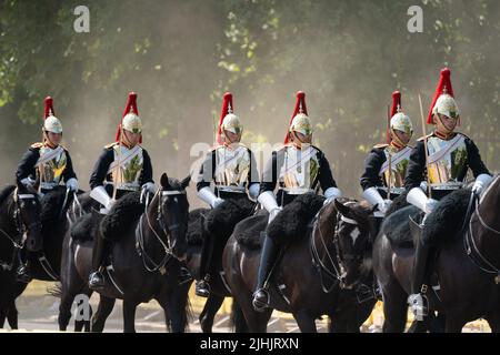 Mitglieder der Household Cavalry schlagen den Staub auf, während sie über die Horse Guards Parade in London fahren, während die Briten den heißesten britischen Tag erleben werden, der seit Jahren auf 40C erwartet wird. Bilddatum: Dienstag, 19. Juli 2022. Stockfoto