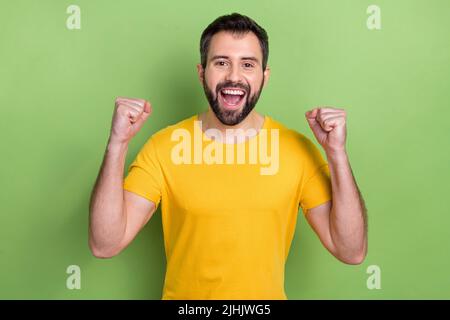 Porträt von überglücklich erfreut Mann heben Fäuste Triumph Leistung isoliert auf grünem Hintergrund Stockfoto