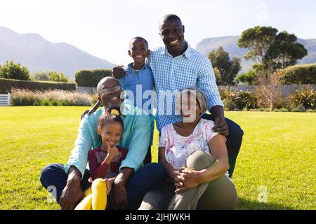 Porträt einer glücklichen multirassischen Familie mit mehreren Generationen, die ihre Freizeit auf dem Rasen im Hof genießt Stockfoto