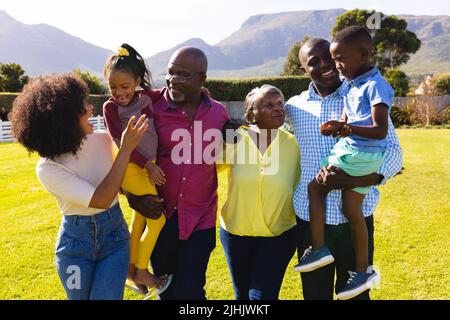 Glückliche multirassische Familie mit mehreren Generationen, die am sonnigen Tag Freizeit im Hof verbringt Stockfoto