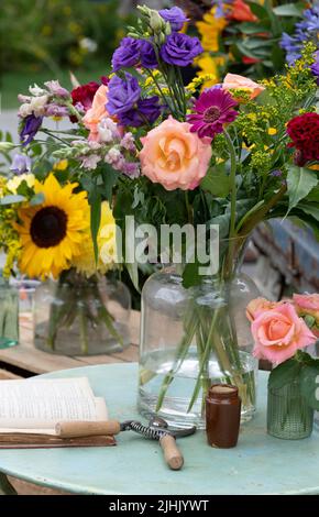 Schneiden Sie Blumen in Glasvasen auf einem Gartentisch. VEREINIGTES KÖNIGREICH Stockfoto