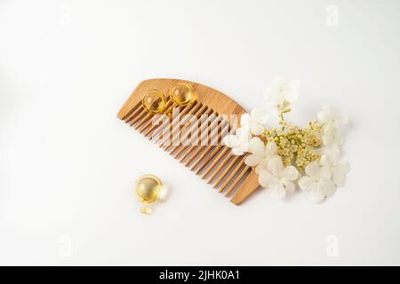 Naturölvitamine goldene Kapseln für Haare, die auf einem Holzkamm liegen Stockfoto