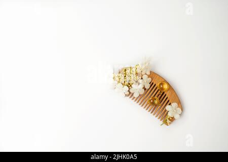 Naturölvitamine goldene Kapseln für Haare, die auf einem Holzkamm liegen Stockfoto