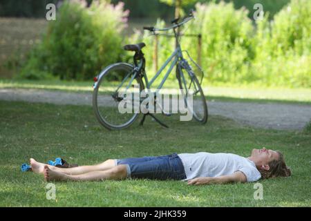 Amsterdam, Niederlande. 19.. Juli 2022. Am 19. Juli 2022 liegt ein Mann im Schatten eines Baumes im Vondelpark in Amsterdam, Niederlande, auf dem Gras. In einigen Regionen der Niederlande wurden Temperaturen von 39 Grad Celsius prognostiziert, das niederländische Wetterbüro (KNMI) gab eine Code-Orange-Wetterwarnung heraus. (Foto von Paulo Amorim/Sipa USA) Quelle: SIPA USA/Alamy Live News Stockfoto