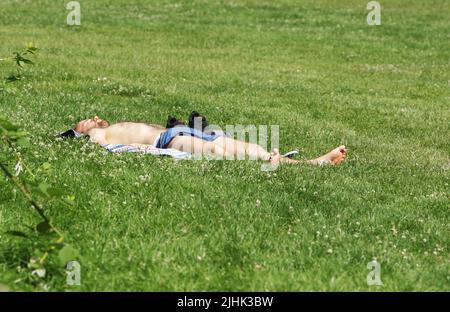 Amsterdam, Niederlande. 19.. Juli 2022. Ein Mann genießt am 19. Juli 2022 in Amsterdam, Niederlande, ein Sonnenbad auf dem Gras im Rembrandt Park. In einigen Regionen der Niederlande wurden Temperaturen von 39 Grad Celsius prognostiziert, das niederländische Wetterbüro (KNMI) gab eine Code-Orange-Wetterwarnung heraus. (Foto von Paulo Amorim/Sipa USA) Quelle: SIPA USA/Alamy Live News Stockfoto