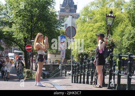 Amsterdam, Niederlande. 19.. Juli 2022. Junge Touristen posieren für ein Foto auf der Straße an der Prinsengracht am 19. Juli 2022 in Amsterdam, Niederlande. In einigen Regionen der Niederlande wurden Temperaturen von 39 Grad Celsius prognostiziert, das niederländische Wetterbüro (KNMI) gab eine Code-Orange-Wetterwarnung heraus. (Foto von Paulo Amorim/Sipa USA) Quelle: SIPA USA/Alamy Live News Stockfoto