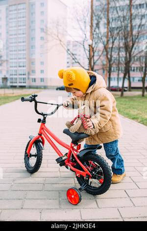 Ein kleines Kind lernt im Frühjahr zum ersten Mal in der Stadt Fahrrad zu fahren Stockfoto