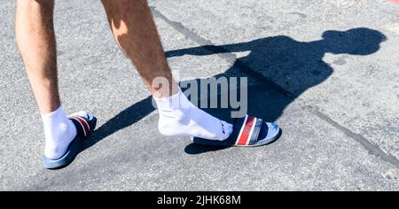 Hannover, Deutschland. 19.. Juli 2022. In der Mittagssonne schlüpft ein Mann in ein Paar Badeslipper. Am Dienstag soll es an vielen Orten in Niedersachsen sehr heiß werden. Quelle: Julian Stratenschulte/dpa/Alamy Live News Stockfoto