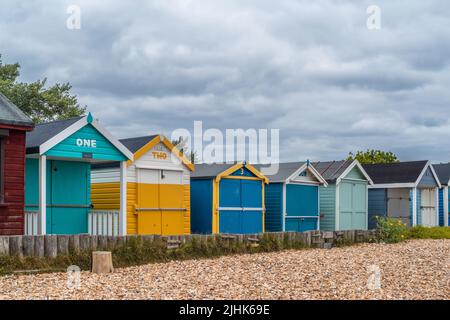 Farbenfrohe, nummerierte Strandhütten am Calshot Beach, Calshot, Hampshire, England, Großbritannien Stockfoto