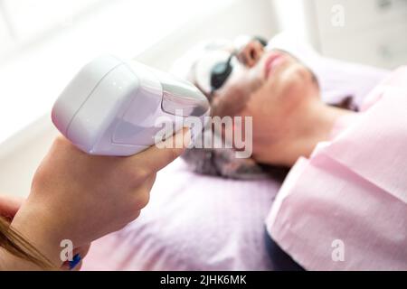 Eine Frau, die auf der Couch liegt, wird gerade einem Carbon-Gesichtspeeling unterzogen. Stockfoto