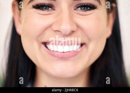 Nahaufnahme einer selbstbewussten jungen kaukasischen Frau mit einem strahlenden und schönen Lächeln. Ein Weibchen sieht nur glücklich und fröhlich aus. Bürsten Sie regelmäßig für Stockfoto