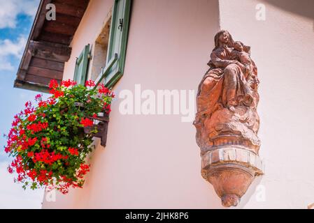 Nische mit der Jungfrau in einer Dazio Hausecke, kleines Haus, das von den Blumen auf seinen Balkonen gefärbt ist. Es war der Sitz der österreichischen Bräuche, während der Th Stockfoto