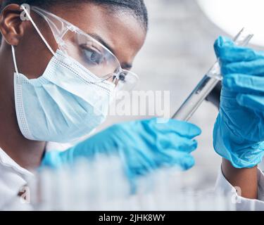 Eine junge Wissenschaftlerin, die in einem Labor mit Reagenzgläsern arbeitet. Stockfoto
