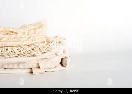 Stapel von umweltfreundlichen Taschen auf einem grauen Hintergrund. Schnur- und Leinenbeutel aus Baumwollfäden. Lifestyle ohne Verschwendung. Öko-Shopper. Wiederverwendbares nachhaltiges Einkaufen. Platz kopieren Stockfoto