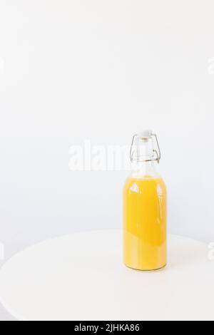 Frisch gepresster Orangensaft in Retro-Flasche mit Stopfen auf dem Tisch, weißer Hintergrund. Gesundes Getränk zum Frühstück. Seitenansicht, Kopierbereich Stockfoto