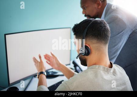 Ich bin auf der gleichen Seite geblieben. Ein nicht erkennbarer Callcenter-Agent sitzt und nutzt seinen Computer, während sein Manager zuschaut. Stockfoto
