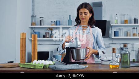 Brunette Hausfrau mit elektrischen Mixer beim Kochen in der Küche Stockfoto