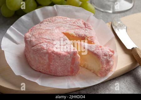 Le Rose, weicher französischer Käse mit Kuhmilch und verfeinert mit Rosé-Champagner und einem Stück Nahaufnahme auf einem Schneidebrett Stockfoto