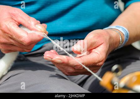 Eine Frau dreht Wolle mit einer modernen Version eines traditionellen Spinnrads. Stockfoto