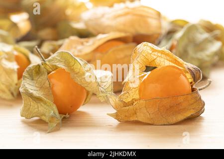 Frische Cape Stachelbeere, Physalis peruviana, mit Schale auf Holzhintergrund aus nächster Nähe Stockfoto