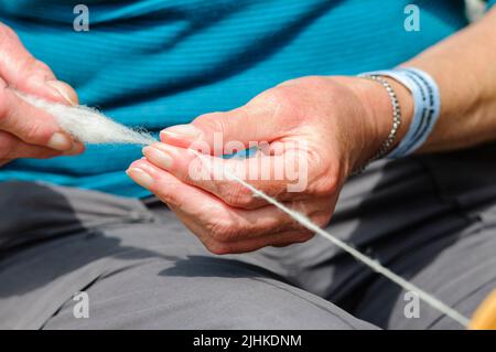 Eine Frau dreht Wolle mit einer modernen Version eines traditionellen Spinnrads. Stockfoto