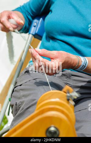 Eine Frau dreht Wolle mit einer modernen Version eines traditionellen Spinnrads. Stockfoto