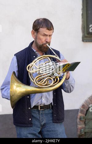 Die Altstadt von Riga ist ein Straßenmusiker, ein Mann im mittleren Alter von 50s Jahren, der auf dem französischen Horn spielt, die Altstadt von Riga, Riga Lettland Europa - Beispiel für den Lebensstil in Riga Stockfoto