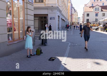 Kinder spielen; Ein Kind Straßenmusiker Riga; ein junges Mädchen im Alter von 10 Jahren singen, um Geld zu sammeln, Riga Altstadt, Riga Lettland Europa Stockfoto