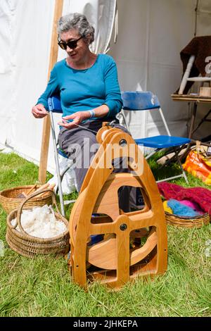 Eine Frau dreht Wolle mit einer modernen Version eines traditionellen Spinnrads. Stockfoto