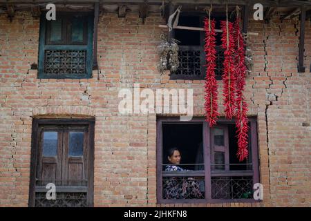 Lalitpur, Nepal. 19.. Juli 2022. Am 19. Juli 2022 in Lalitpur, Nepal. Frauen schauen durch das Fenster, wo rote Chilis zum Trocknen aufbewahrt werden, nachdem sie sie im Altetal von Khokhana gewebt haben. (Foto: Abhishek Maharjan/Sipa USA) Quelle: SIPA USA/Alamy Live News Stockfoto