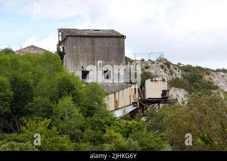 Asbest verkleideter shoreham-Zement arbeitet jetzt verfällt mit Stütztürmen und Förderern gebrochene Fenster und Asbestplatten ein braunes Feld-Gelände eingezäunt Stockfoto