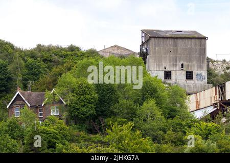 Asbest verkleideter shoreham-Zement arbeitet jetzt verfällt mit Stütztürmen und Förderern gebrochene Fenster und Asbestplatten ein braunes Feld-Gelände eingezäunt Stockfoto